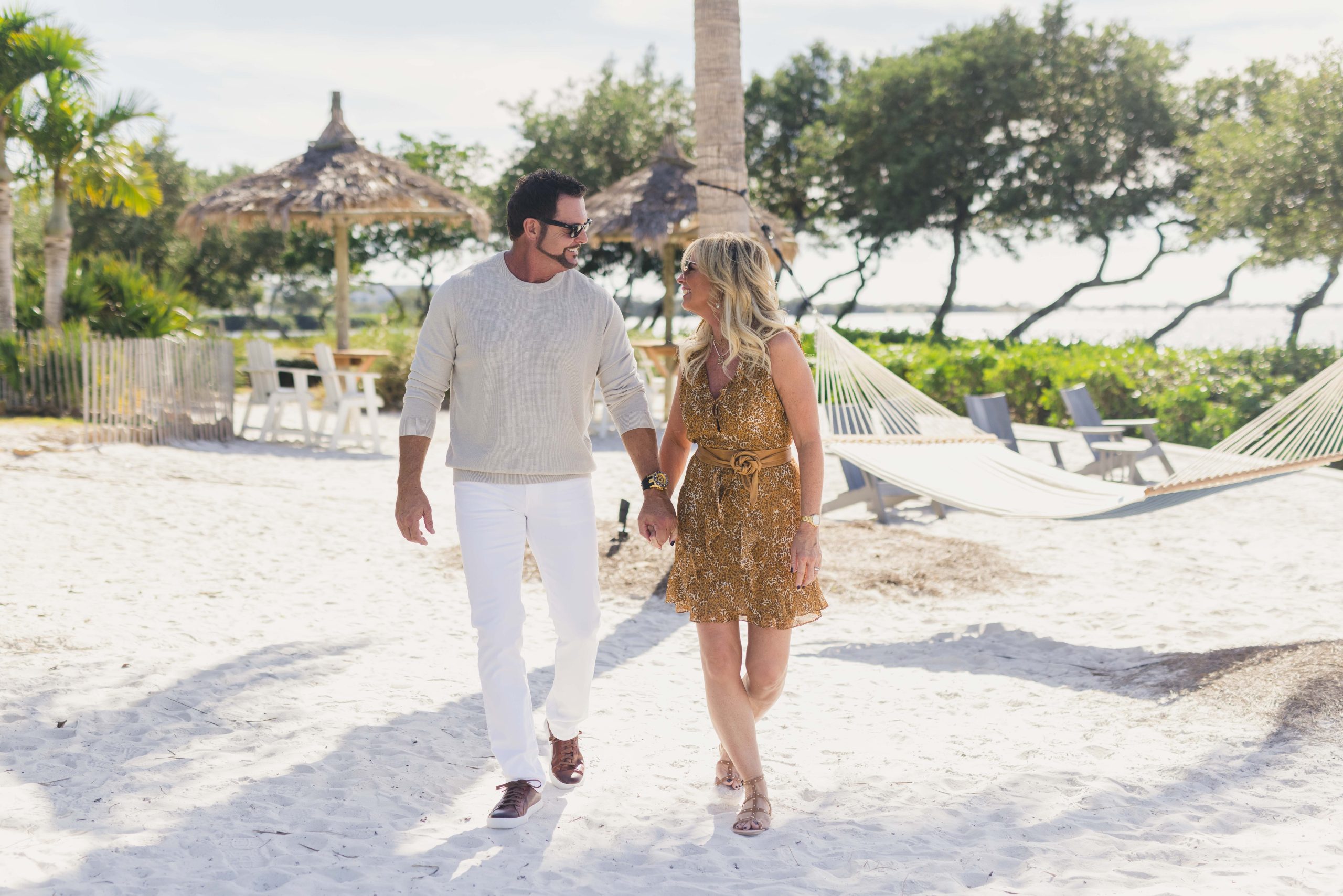 A couple gazes deeply into each other's eyes as they walk along the white sandy beach